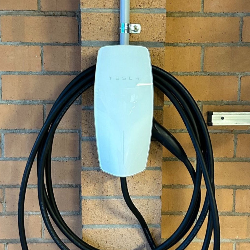 Tesla wall connector gen3 with charging cable attached to the wall.