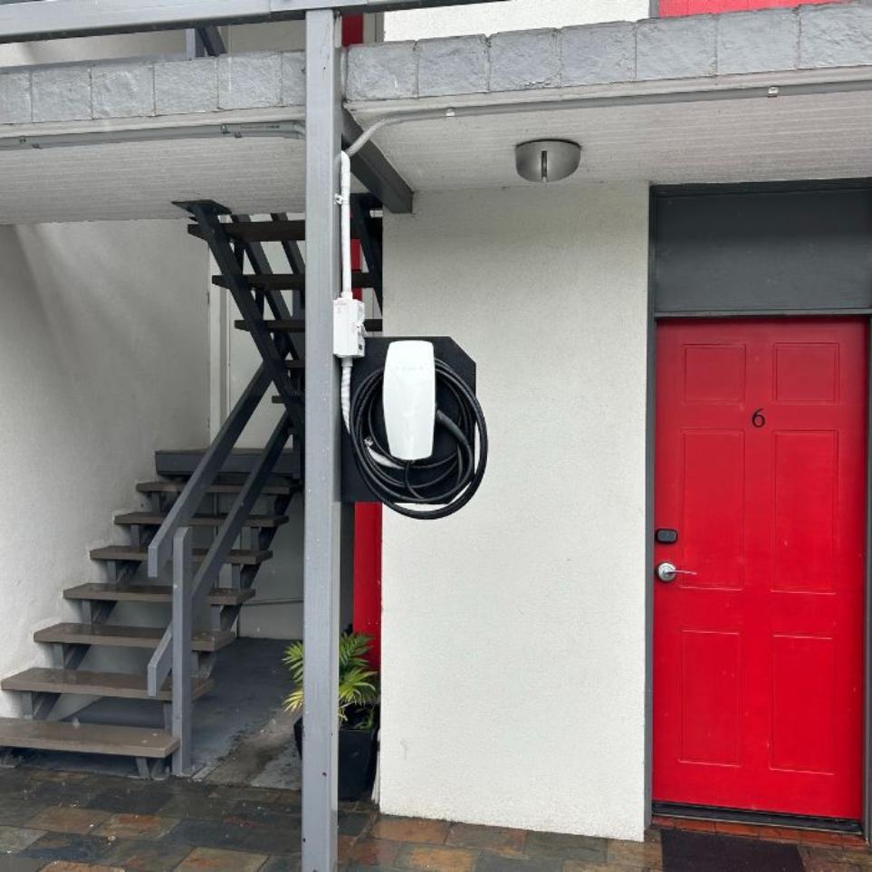 Tesla wall connector EV charger mounted on an existing post in the carpark.
