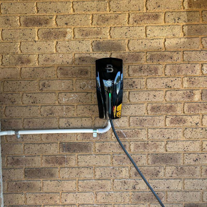 Black Beny ev charger attached to a brick wall.