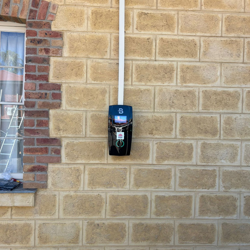 black EV charging station mounted on a brick wall