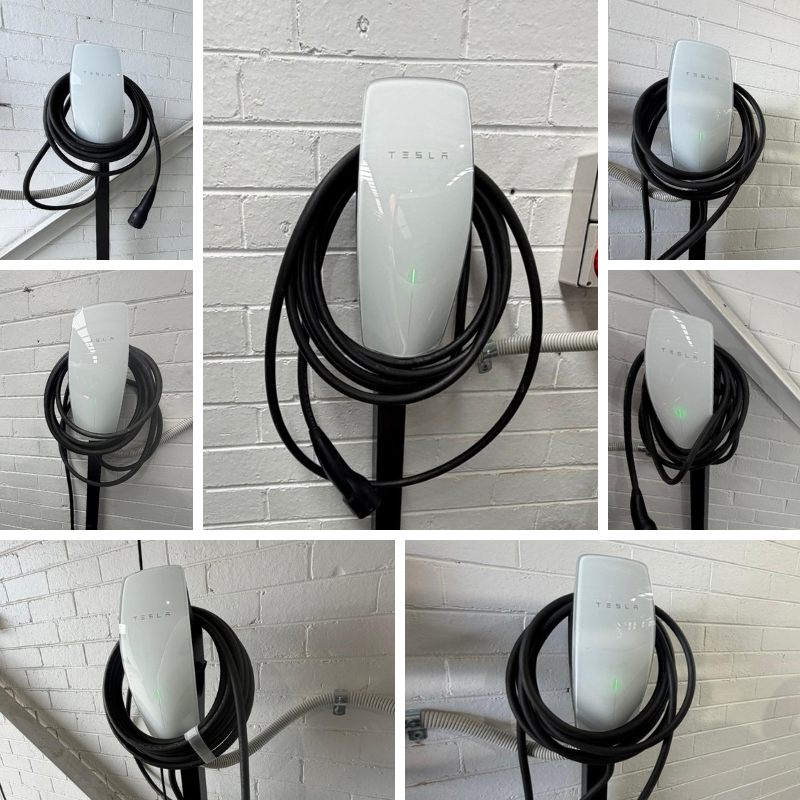 Tesla electric vehicle charging station on a white brick wall.