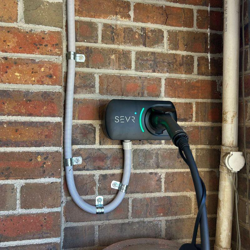 SEVR electric vehicle charging station attached to a brick wall.