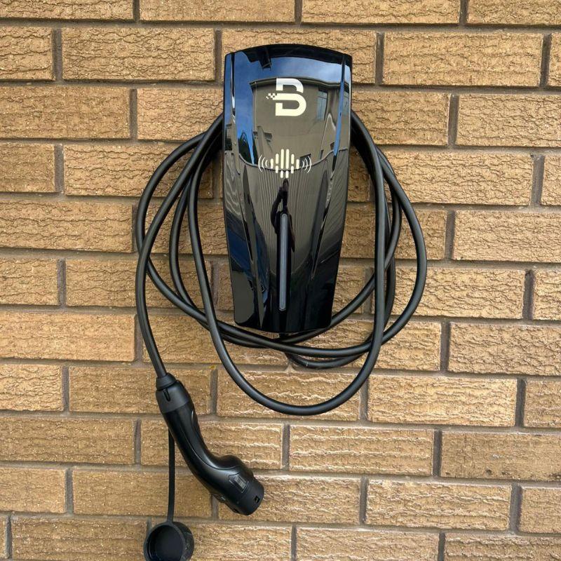 Black Beny electric vehicle charging station mounted on a brick wall