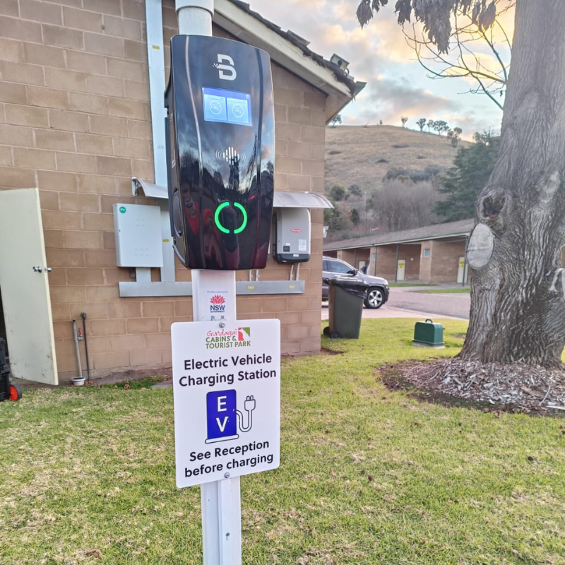 Electric vehicle charging station with a sign in front of a building.