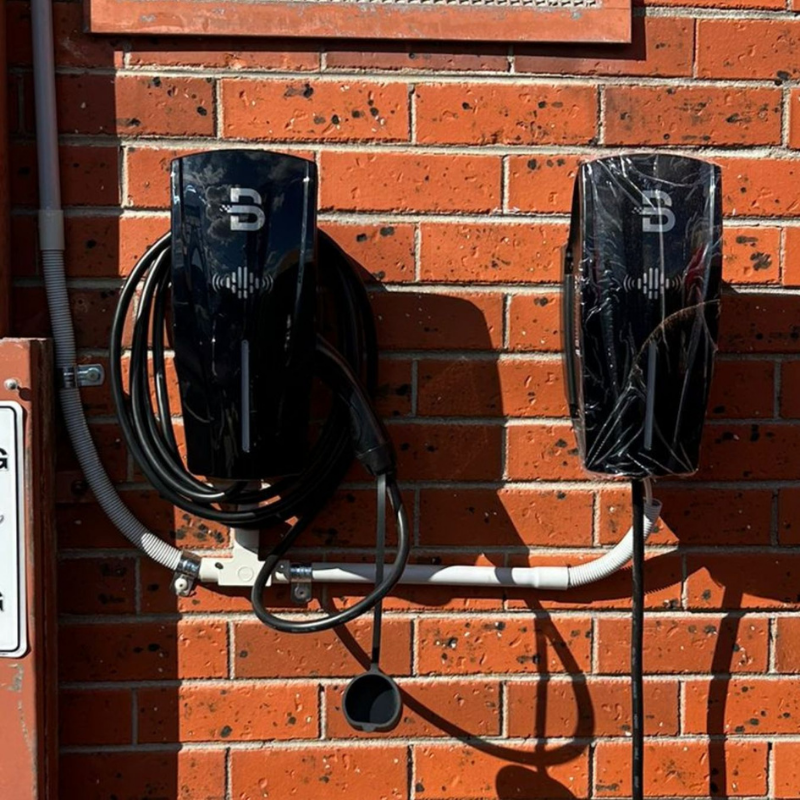 Two electric vehicle charging stations mounted on a brick wall.