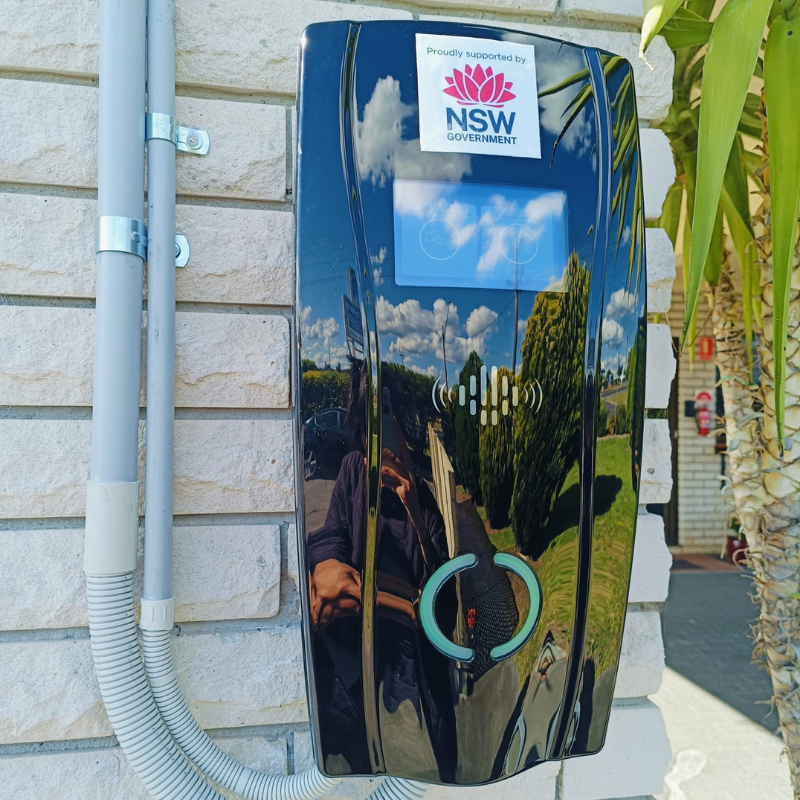 Installed on a brick wall is a black EV charging device