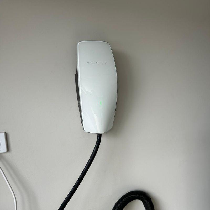 Tesla electric vehicle charging station on a beige wall.