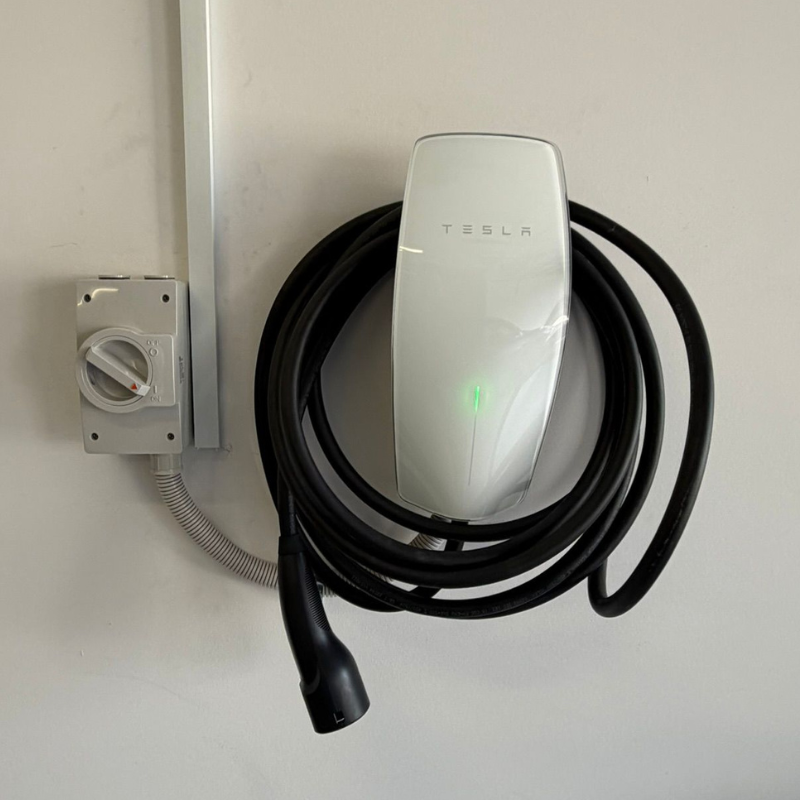 Tesla Wall Connector mounted on a white wall