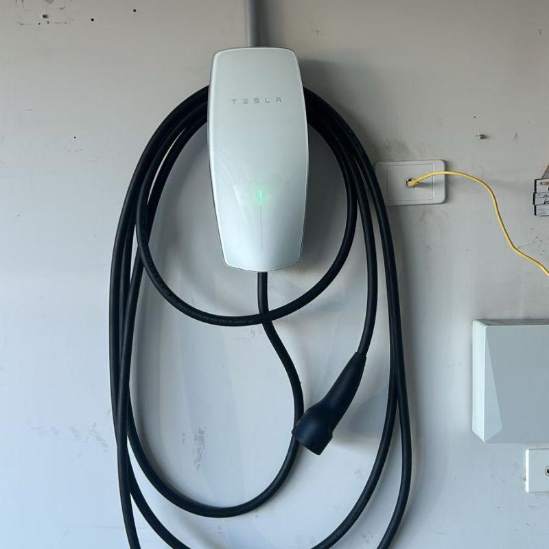 White Tesla wall connector with cable installed on a garage