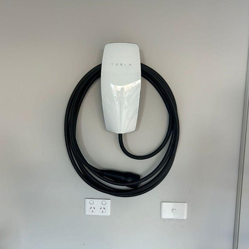 Tesla Gen 3 electric vehicle charging cable attached to a white wall 