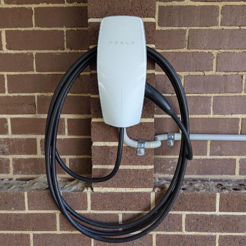 White Tesla wall charger mounted on brick wall
