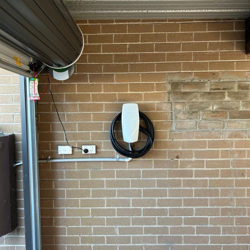 white tesla wall charger mounted on a brick wall