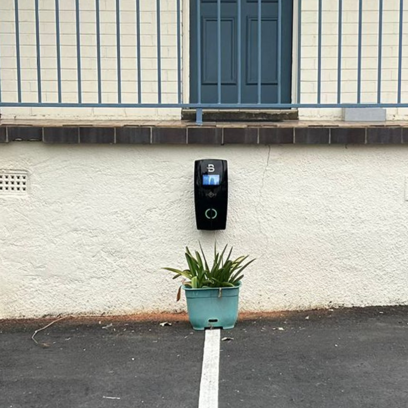 Black EV charging device mounted on a white wall 