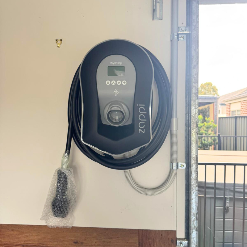 black zappi ev charger mounted on a white wall